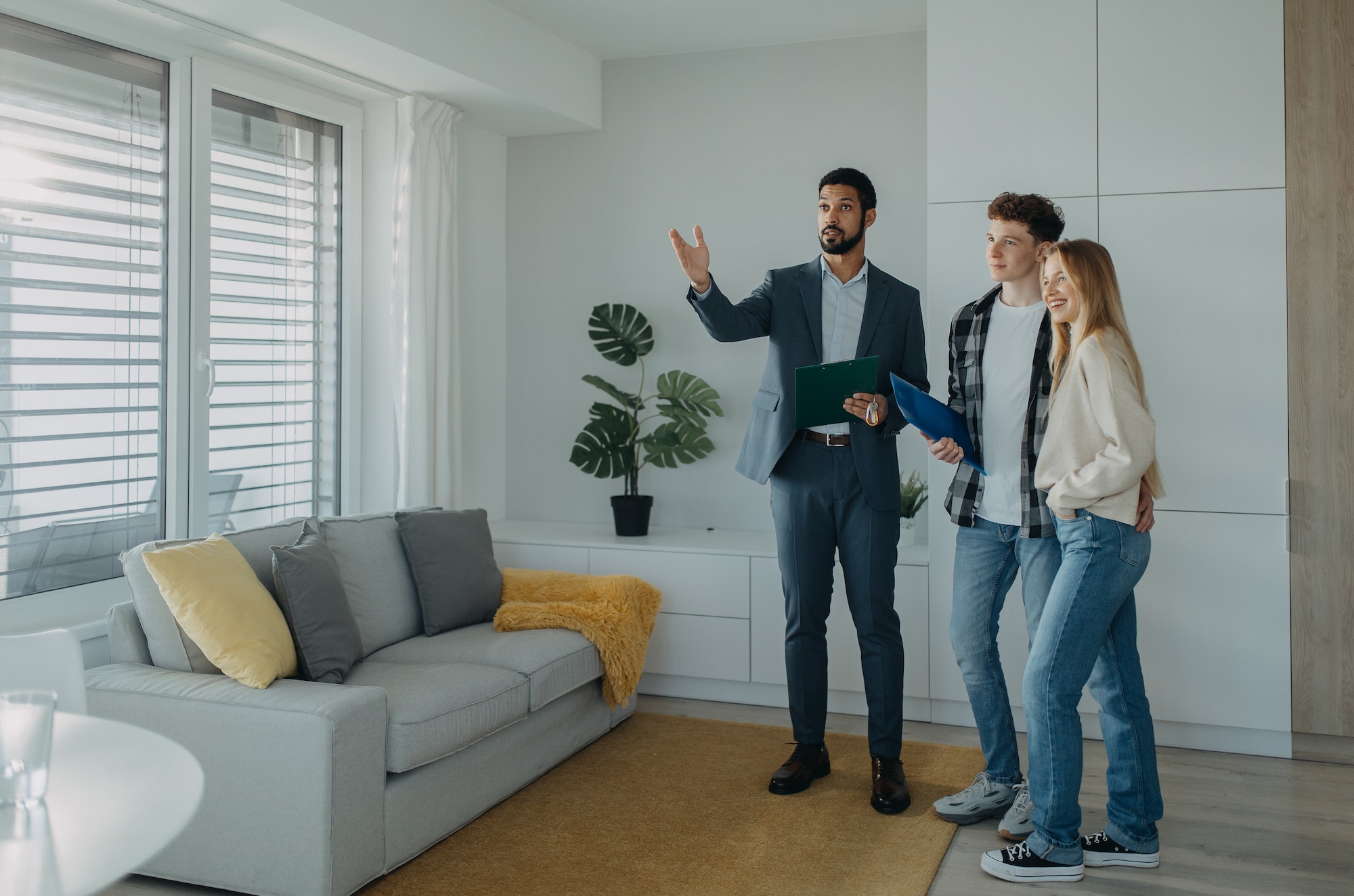 Happy young couple buying their new home and meeting real estate agent in apartment.