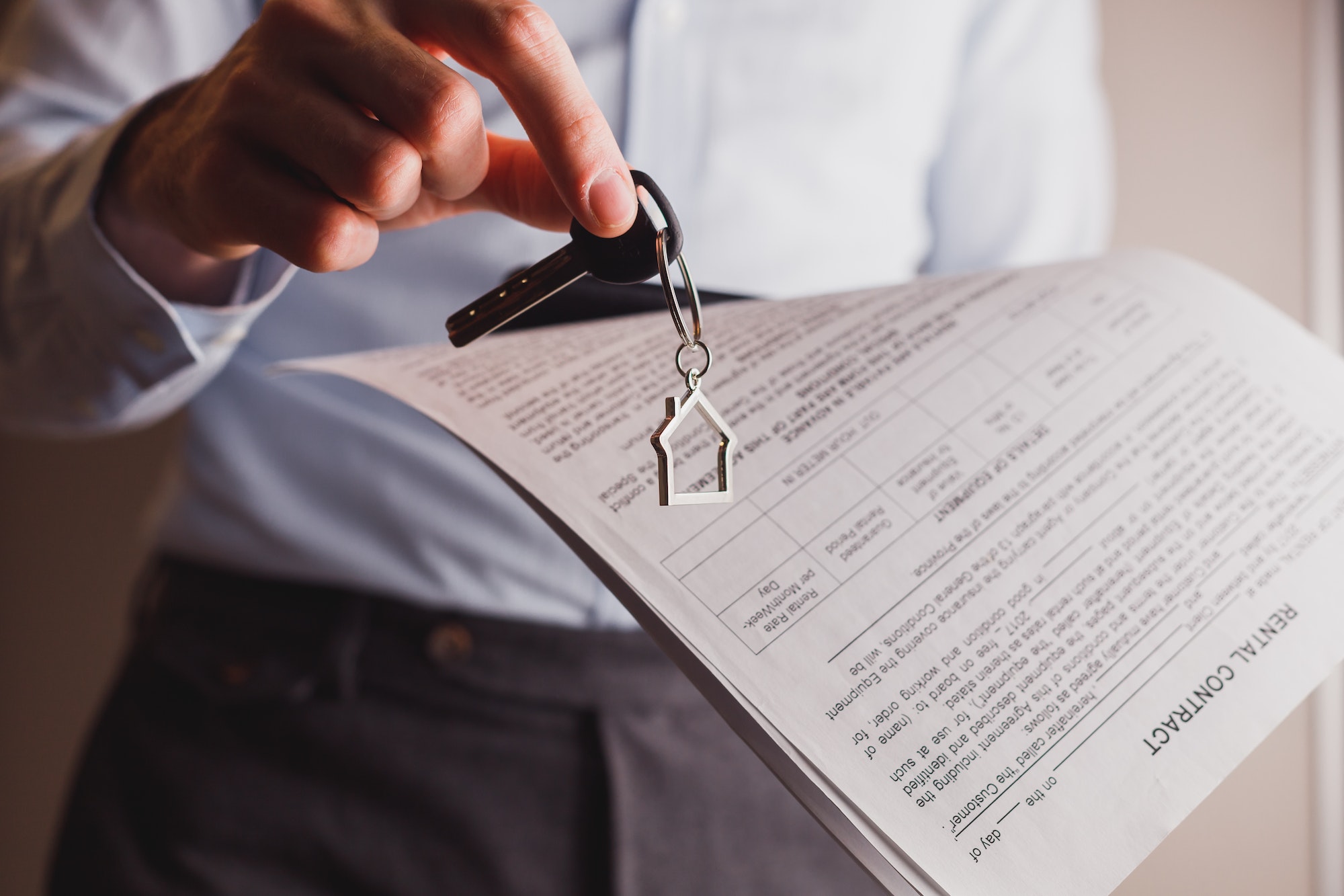 Manager offers keys to house holding contract in other hand. Rental and buying a property