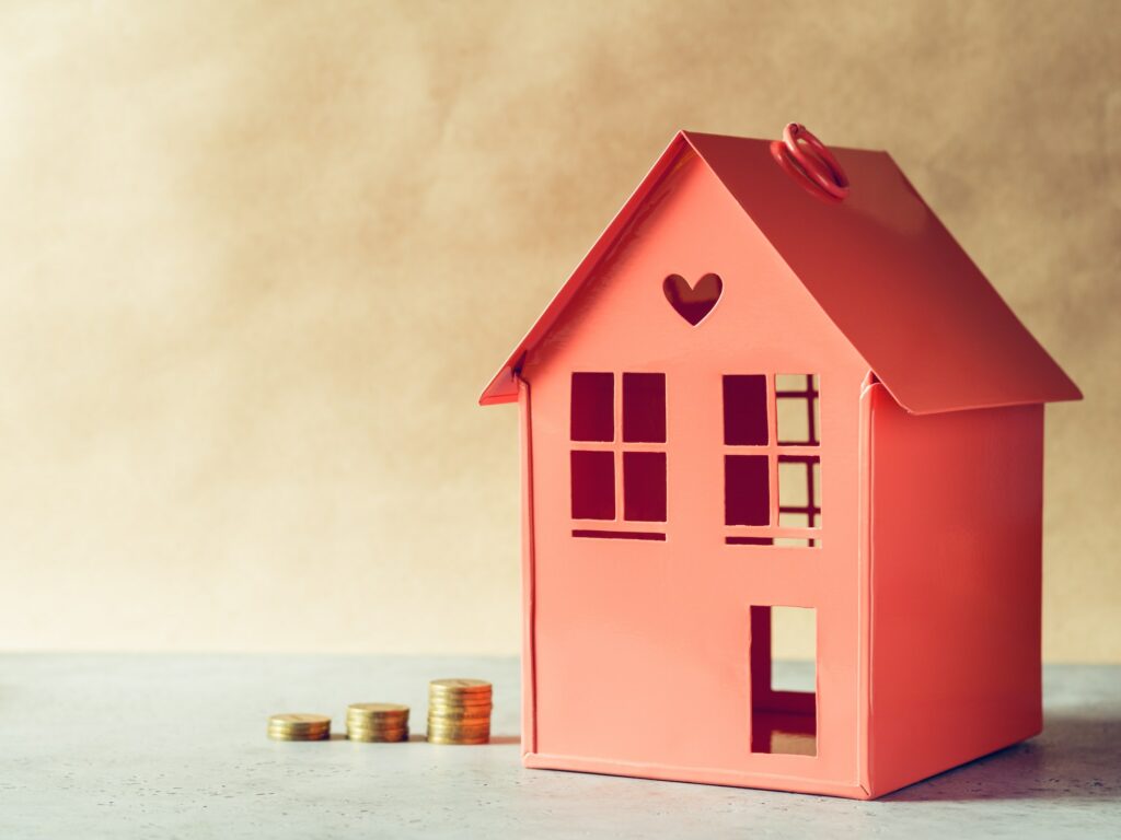 Metal red model of a house and stairs of golden coins. The concept rental or buying the estate.