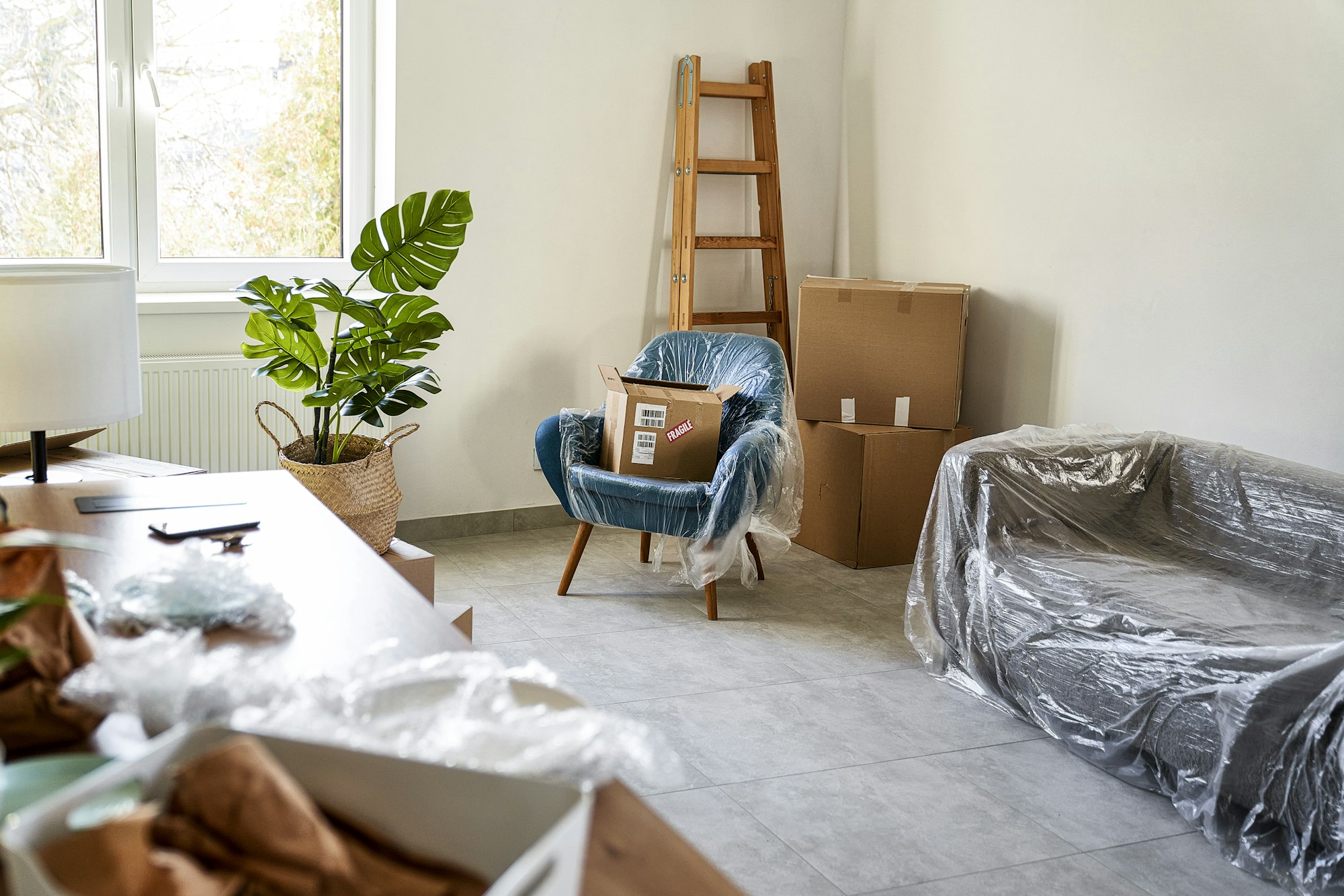 Empty flat with carton boxes and furnitures covered with plastic foil